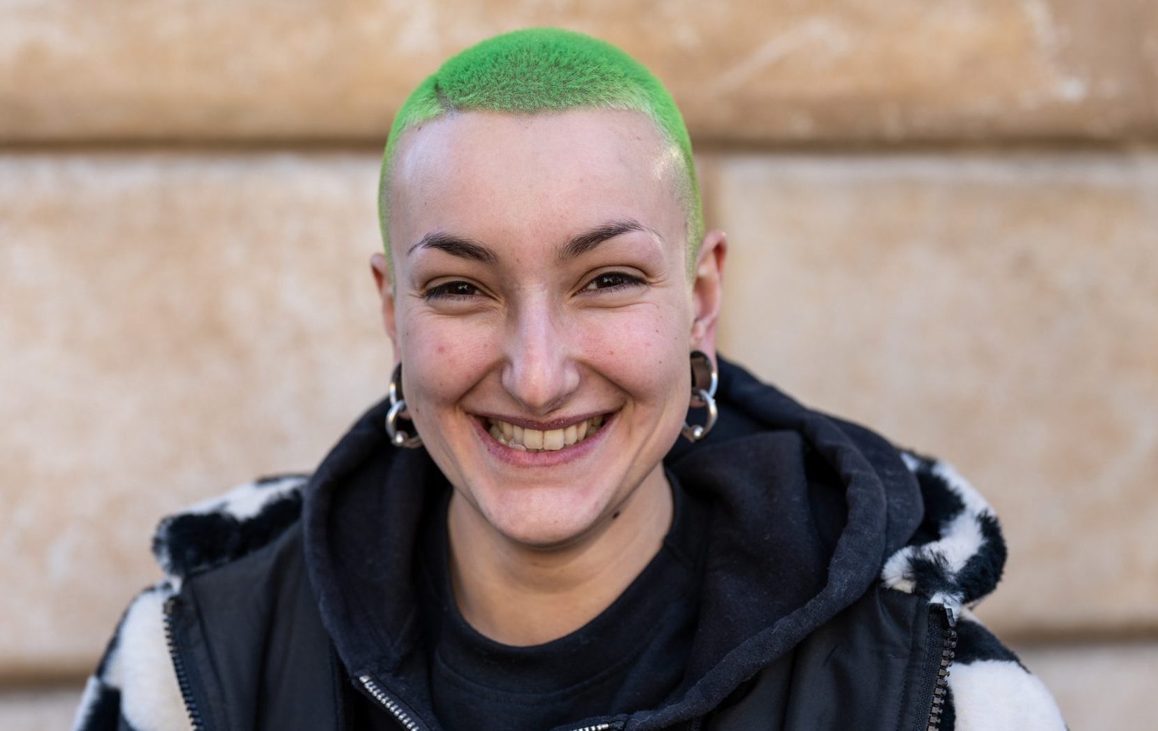 A smiling woman with cropped green hair