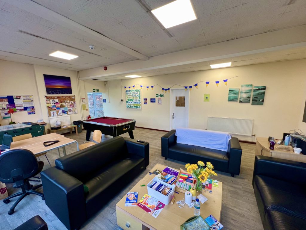 the main lounge area of our Watford crisis cafe, which has three sofas, tables, chairs, a pool table and art on the walls