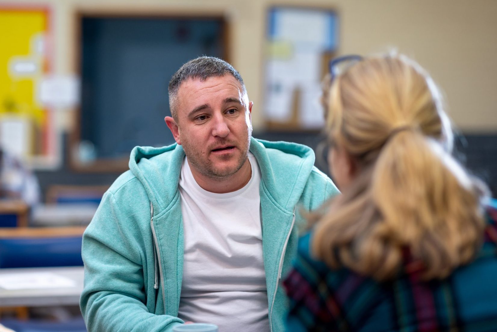 A man in a mint green hoodie talking to a woman