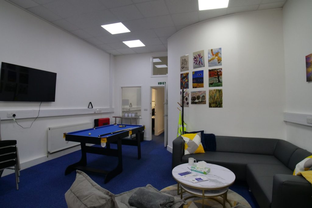 the photo shows an inside room from our Hatfield crisis cafe, including a television, sofa, kitchen area and chairs